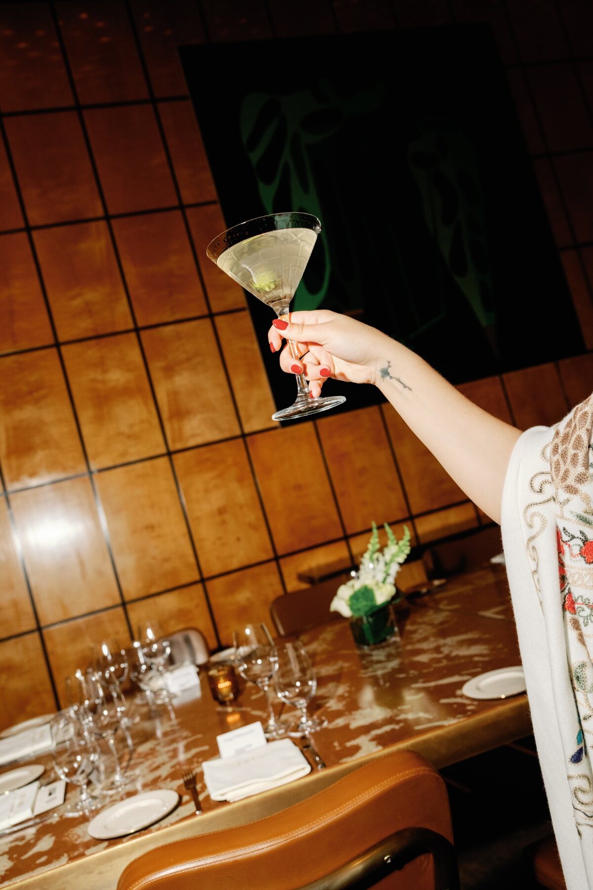 Guest raising a cocktail beside an intentionally set Headliner dinner table